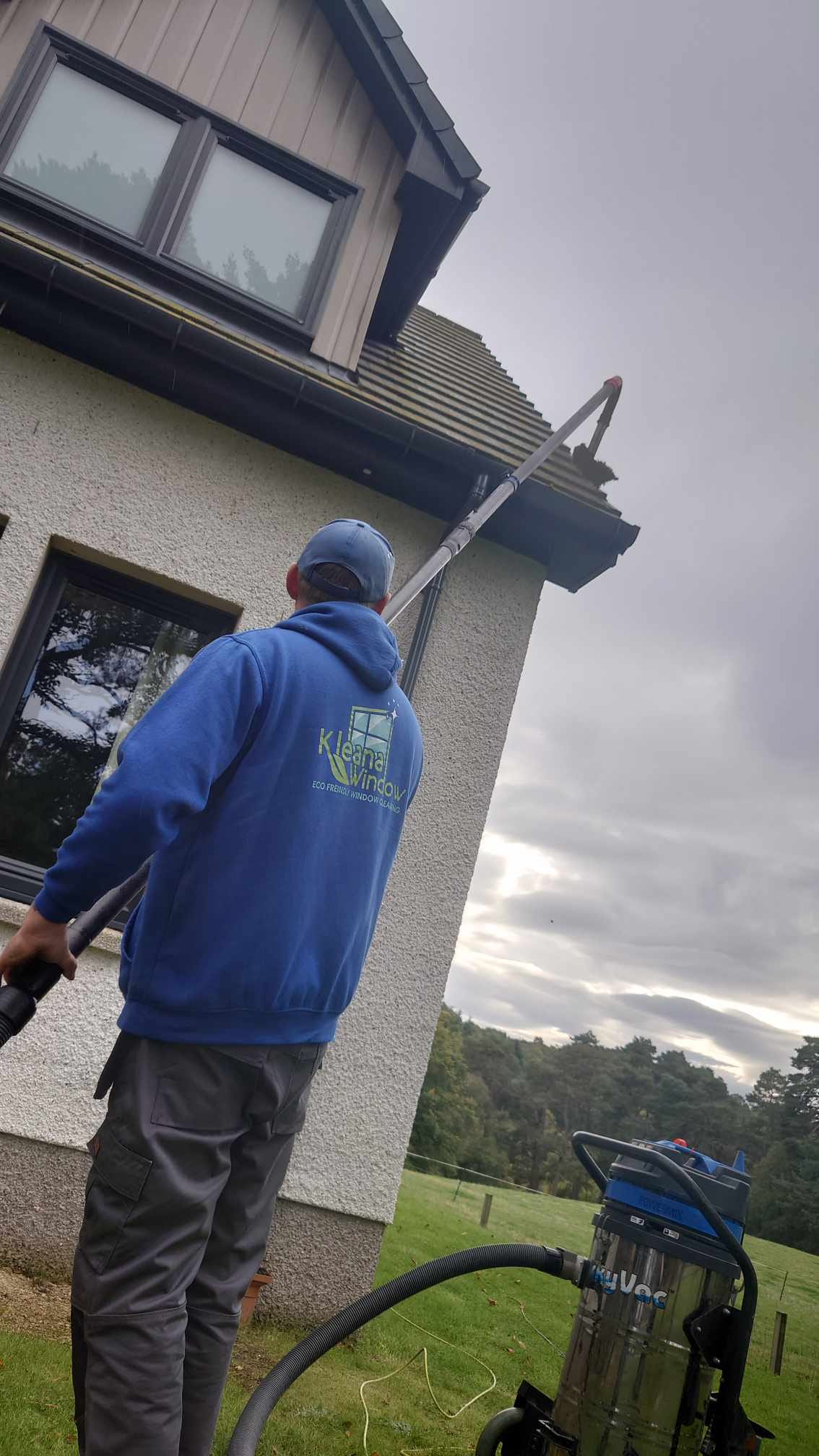 Kleana Window team member cleaning gutters with professional equipment - Inverness service