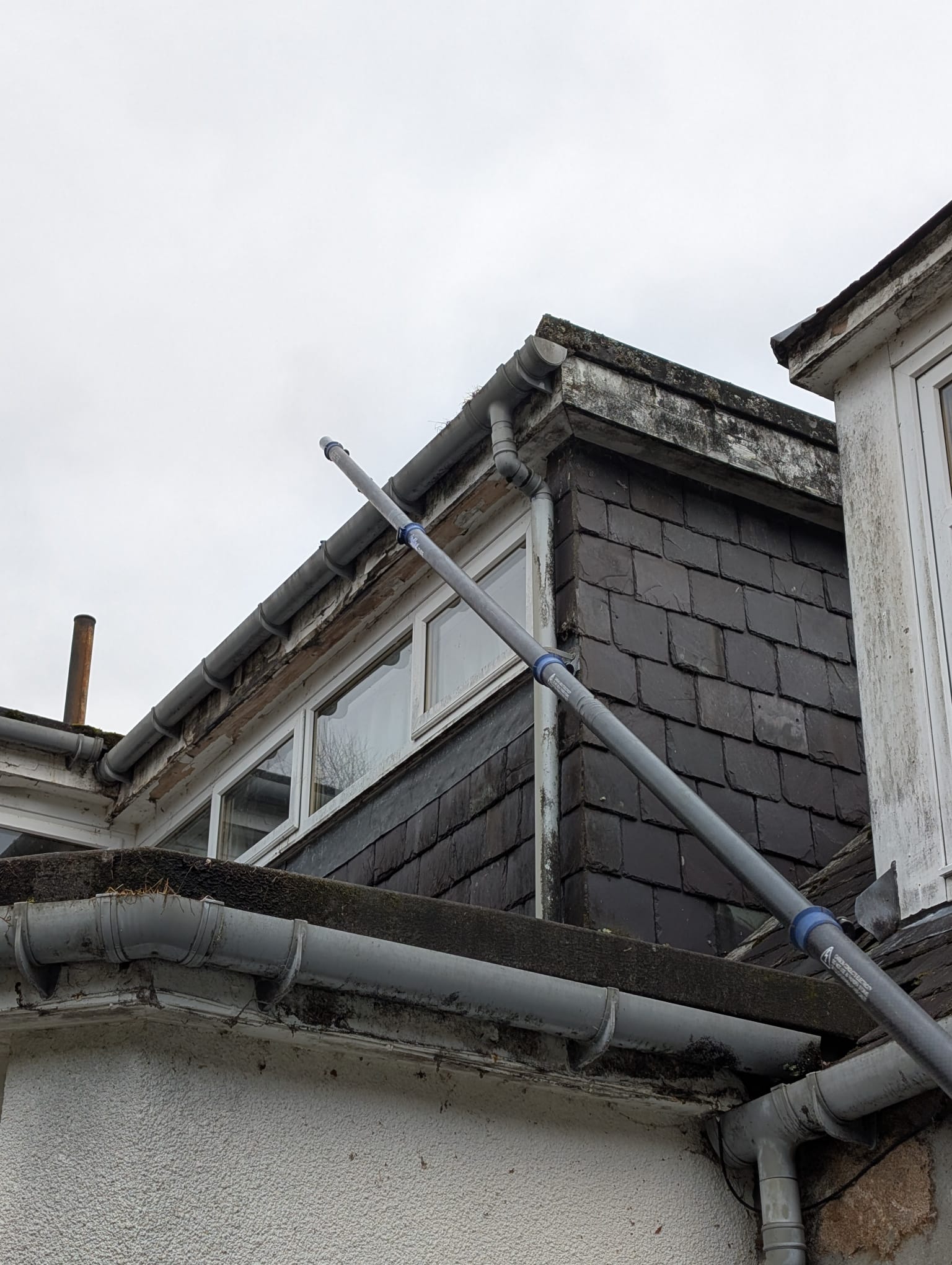 Gutter cleaning service on slate roof showing professional technique